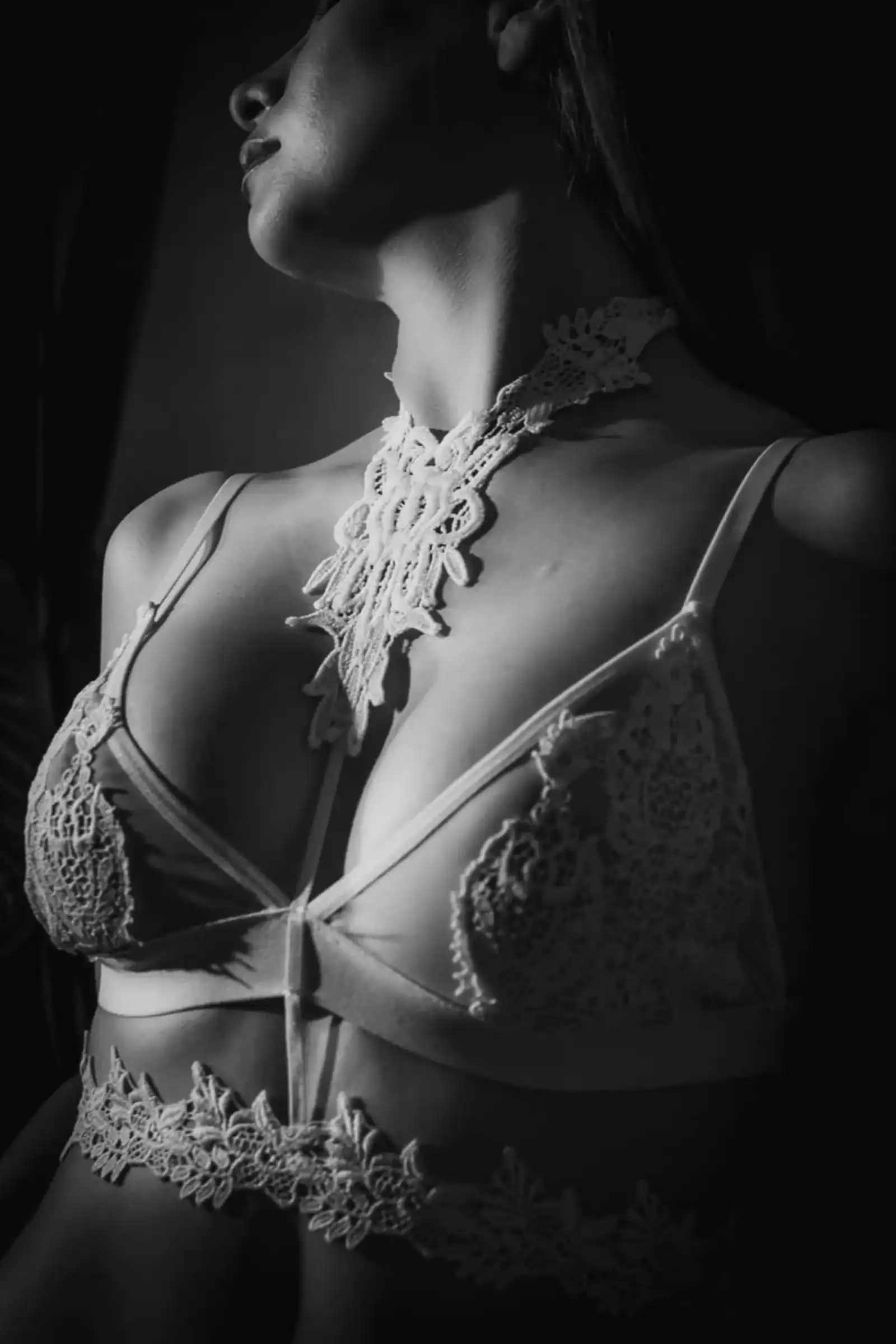 Figura femenina erguida con contraste direccional y texturas de encaje en blanco y negro