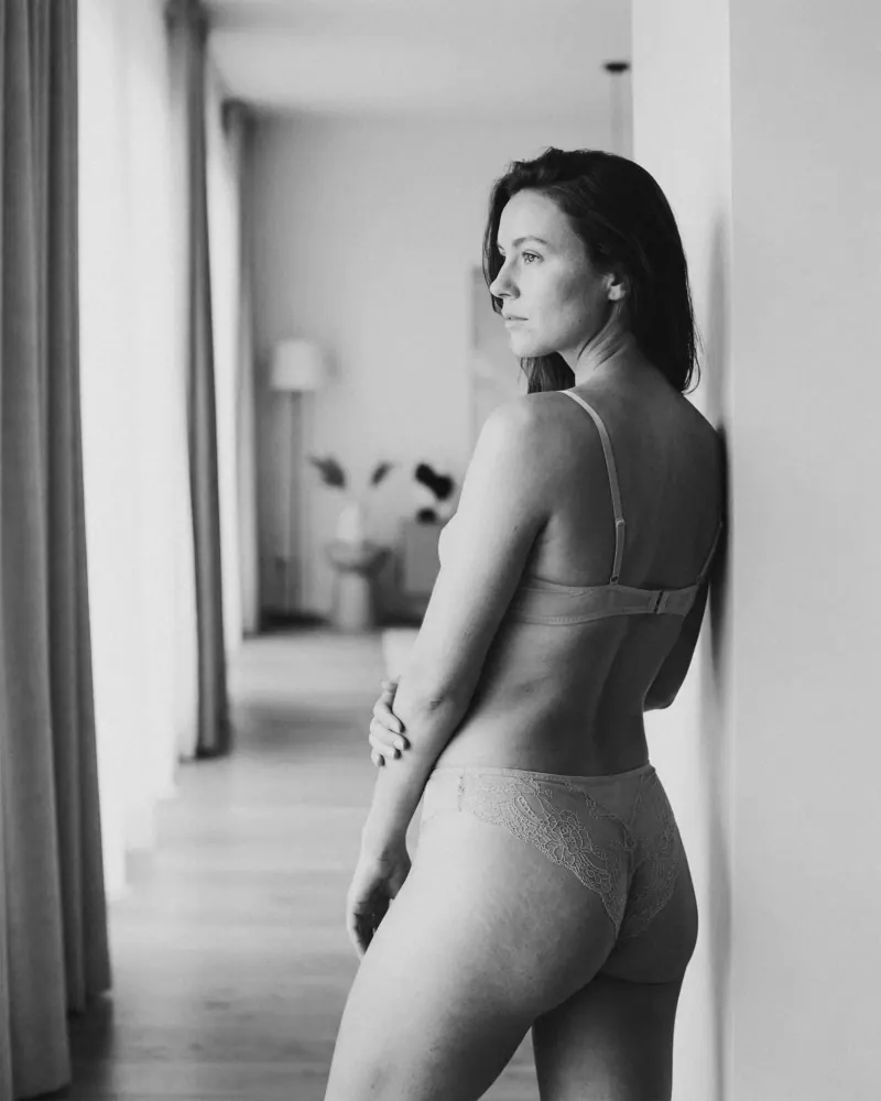Giro de torso con mirada sobre el hombro en blanco y negro, pose boudoir en pasillo