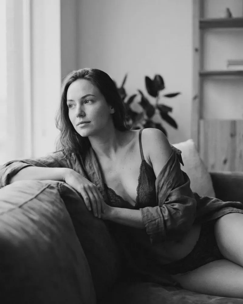 Mujer recargada en sillón con mirada lateral en blanco y negro, retrato boudoir