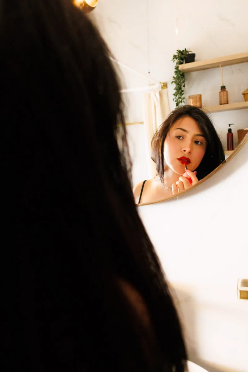 Mujer aplicándose labial rojo frente al espejo del baño, sesión boudoir individual CDMX