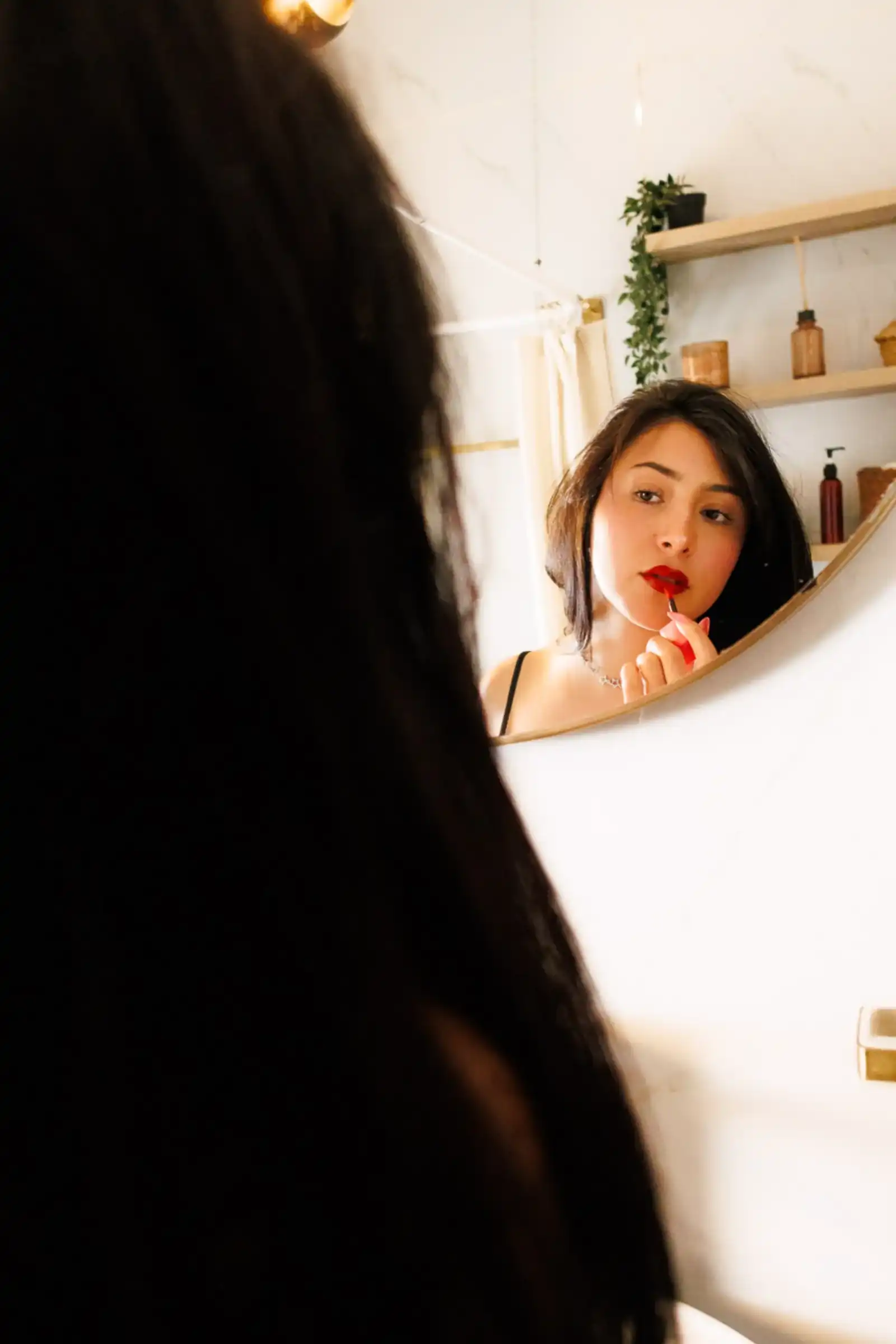 Mujer aplicándose labial rojo frente al espejo del baño, sesión boudoir individual CDMX